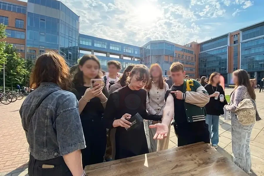 Оператор тату-принтера наносит временную татуировку гостю на мероприятии